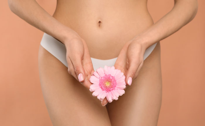 Femme qui tient une fleur devant son bas ventre pour symboliser la flore vaginale